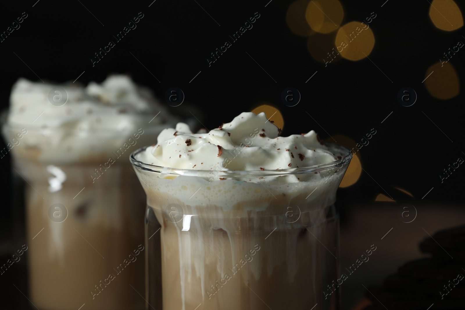 Photo of Glasses of iced coffee against blurred lights, closeup