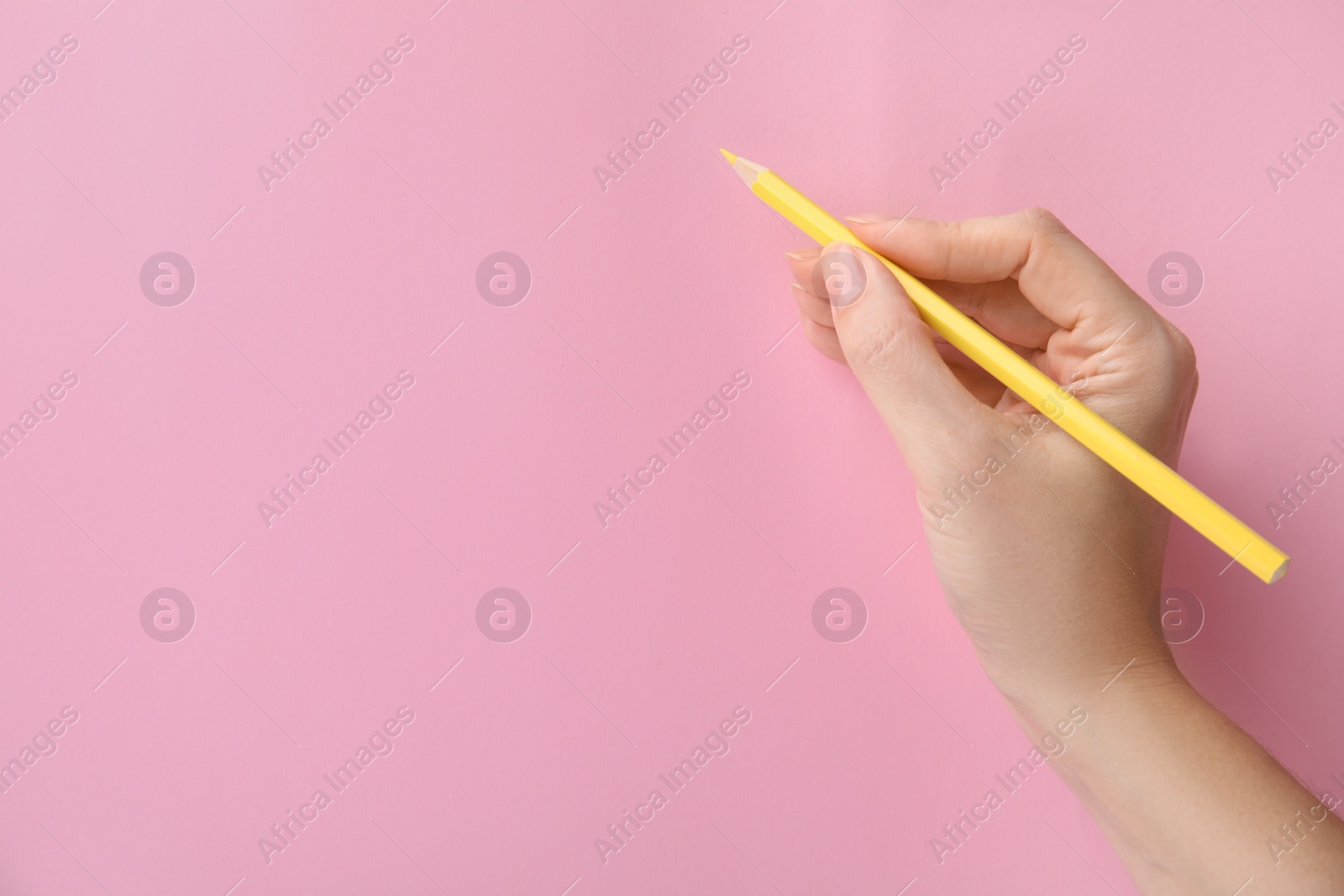 Photo of Woman with yellow pencil on pink background, closeup. Space for text