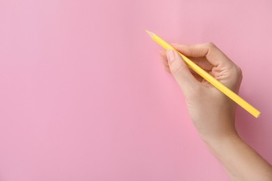 Photo of Woman with yellow pencil on pink background, closeup. Space for text