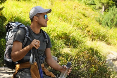 Photo of Hiker with trekking poles resting outdoors on sunny day