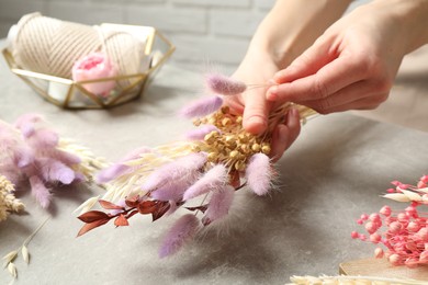 Photo of Florist making bouquet of dried flowers at grey stone table, closeup