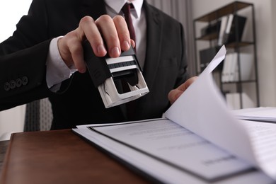 Notary stamping document at table in office, low angle view