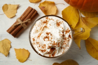 Photo of Delicious pumpkin latte on white table, top view
