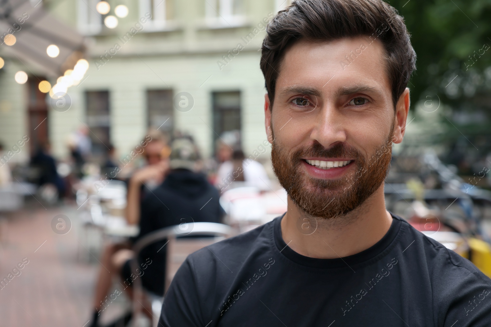 Photo of Portrait of handsome bearded man in outdoor cafe, space for text