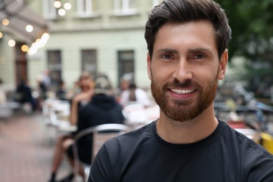 Photo of Portrait of handsome bearded man in outdoor cafe, space for text