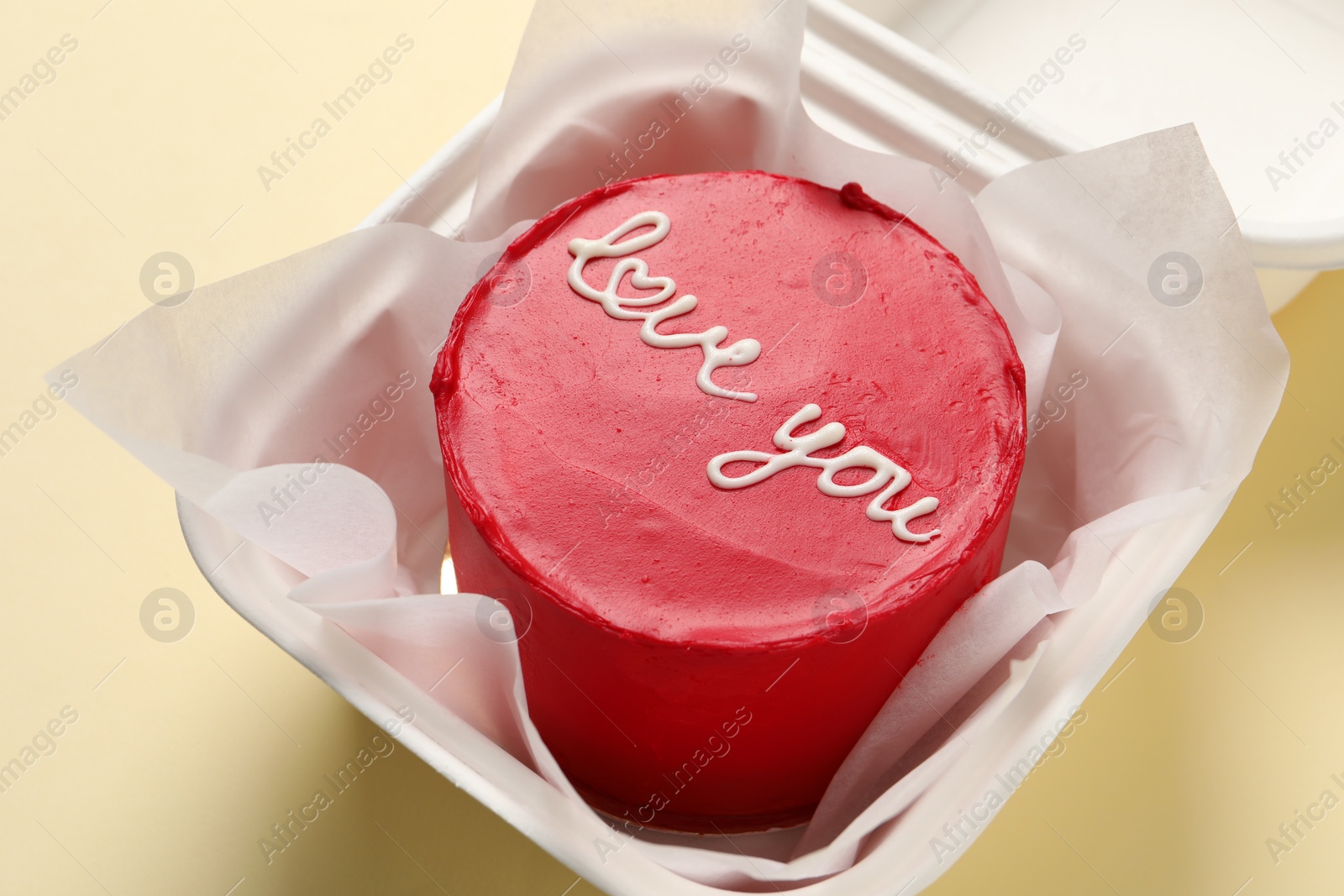 Photo of Bento cake with Love You text in takeaway box on beige table, closeup. St. Valentine's day surprise