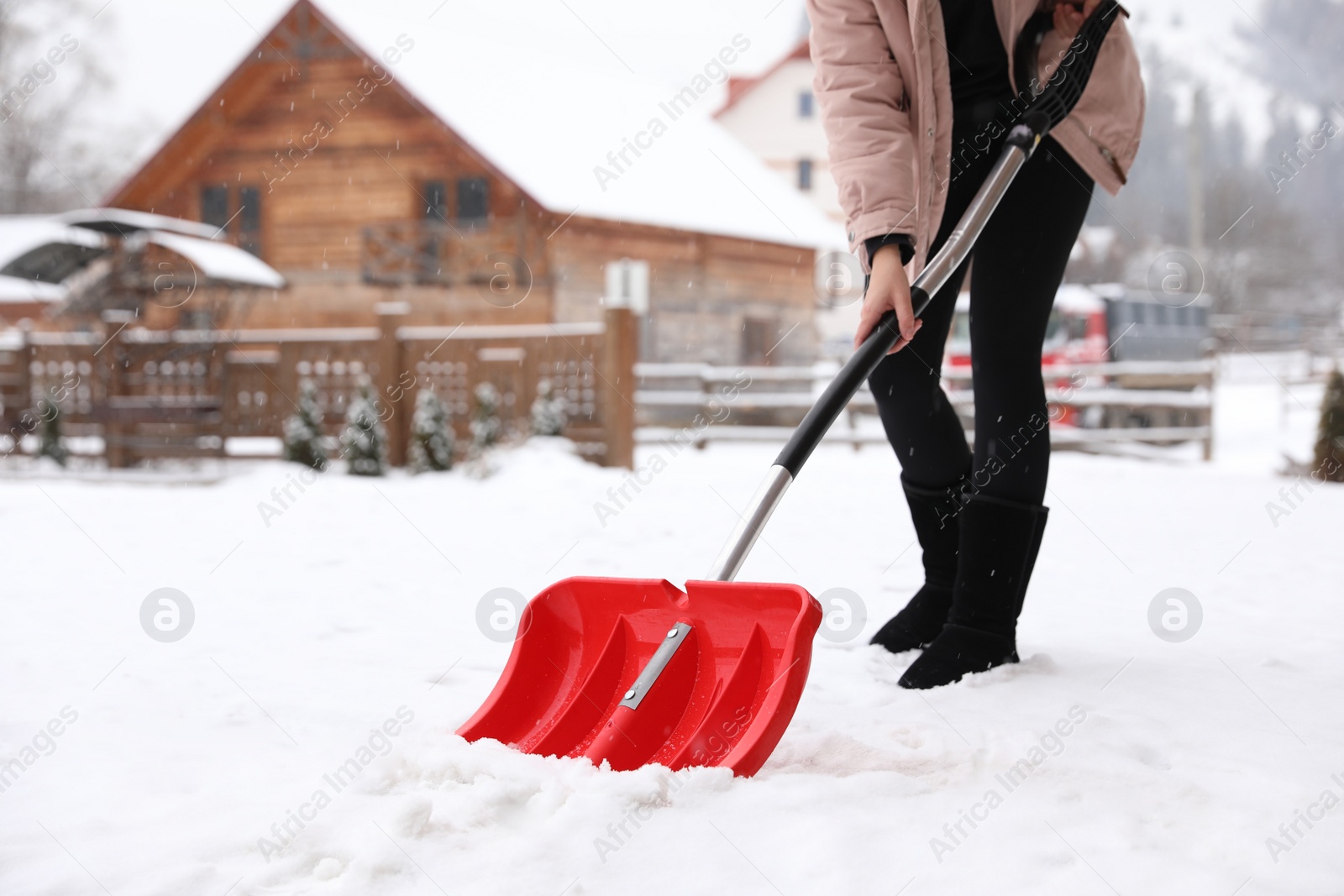 Photo of Young woman cleaning snow with shovel near her house. Space for text