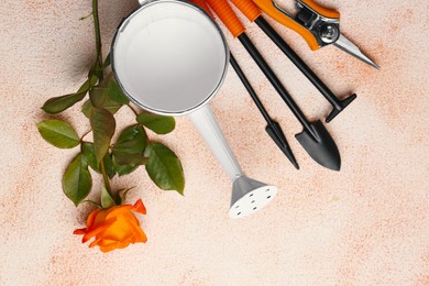 Watering can, gardening tools and rose on color textured background, flat lay