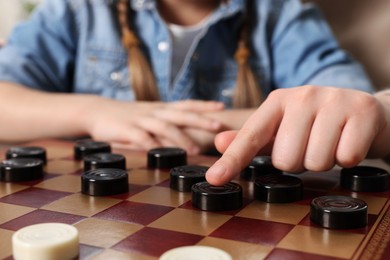 Photo of Playing checkers. Mother learning her daughter at table, closeup
