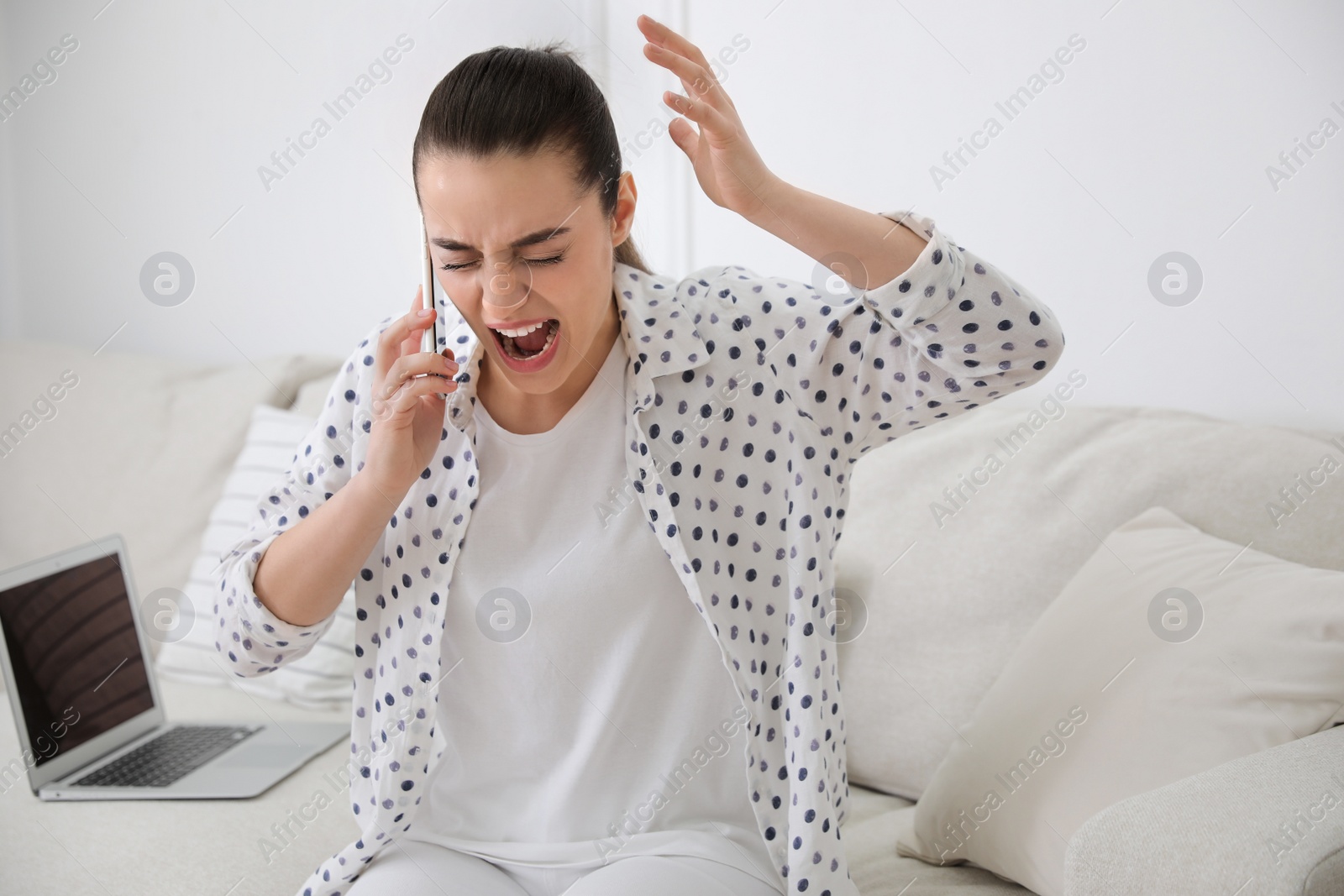 Photo of Emotional young woman talking on smartphone at home. Hate concept