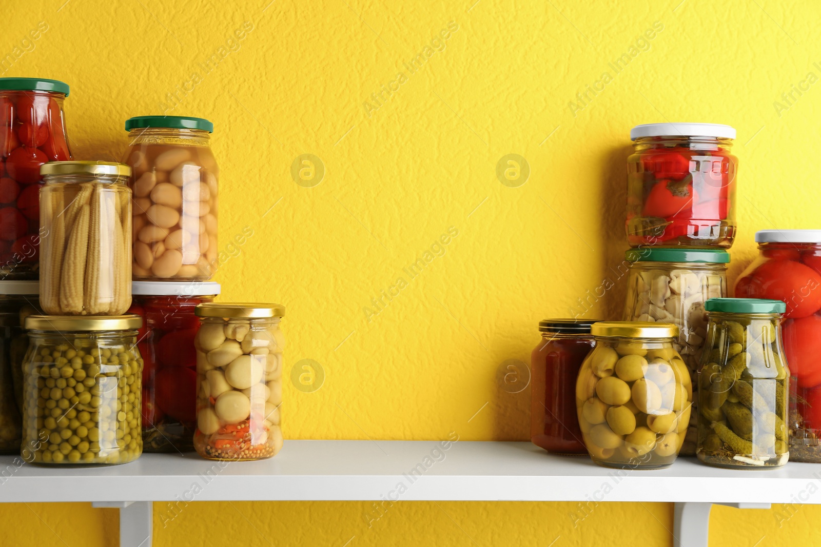 Photo of Jars of pickled vegetables on white wooden shelf. Space for text
