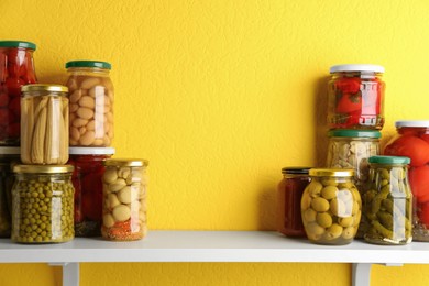 Jars of pickled vegetables on white wooden shelf. Space for text