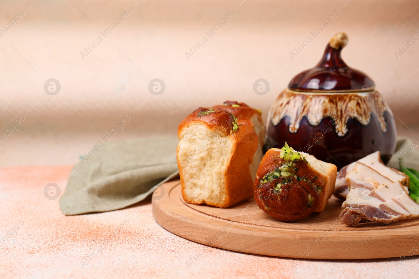 Photo of Delicious pampushky (buns with garlic) and salo served for borsch on color textured table, space for text