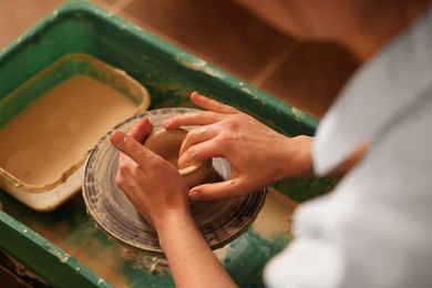 Photo of Clay crafting. Woman making bowl on potter's wheel, closeup