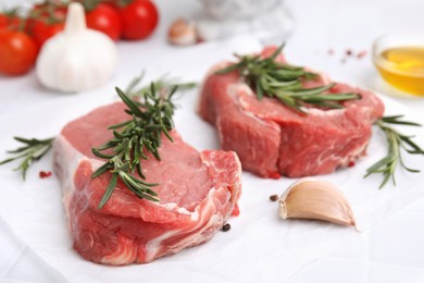 Fresh raw meat with rosemary and spices on parchment paper, closeup