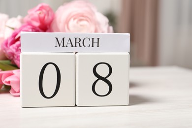 Photo of International Women's day - 8th of March. Block calendar and bouquet of beautiful flowers on white wooden table, closeup