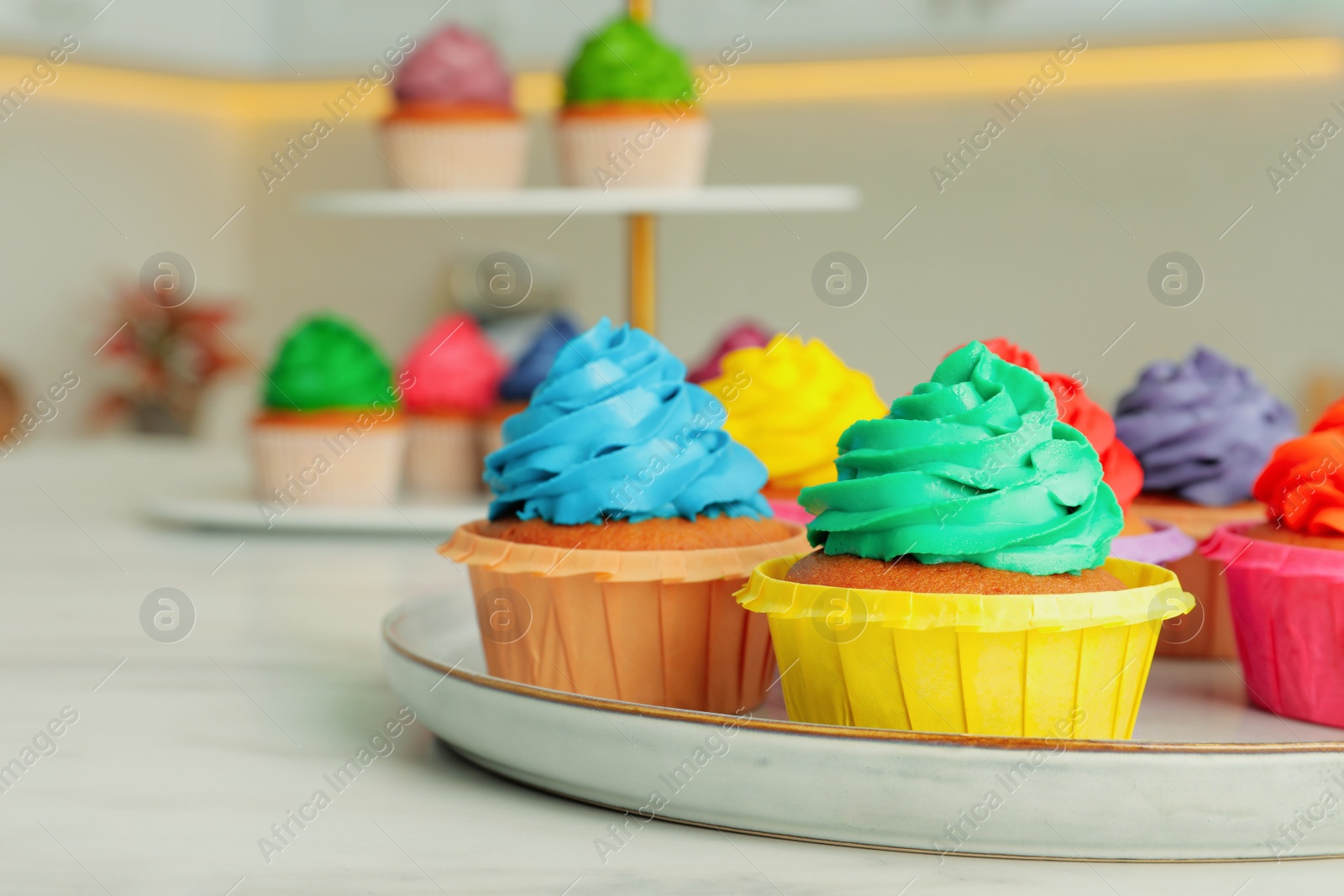 Photo of Delicious cupcakes with colorful cream on white table
