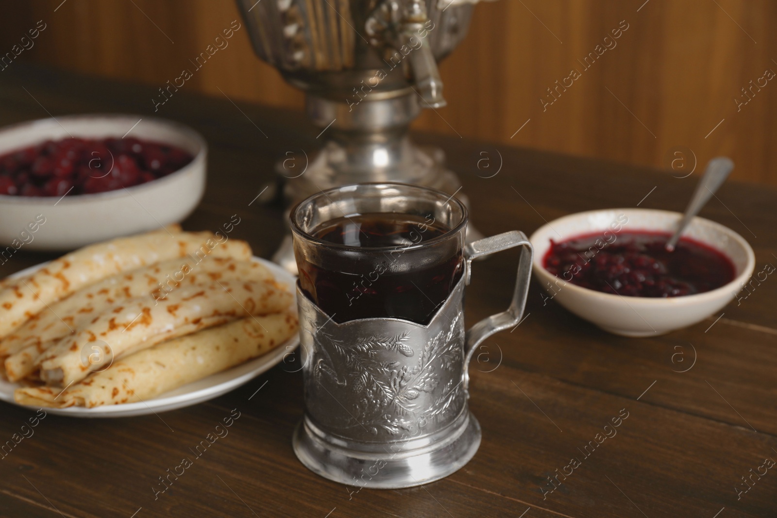 Photo of Vintage samovar, cup of hot drink and snacks served on wooden table. Traditional Russian tea ceremony