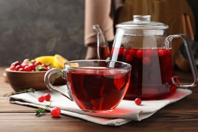 Photo of Tasty hot cranberry tea and fresh berries on wooden table