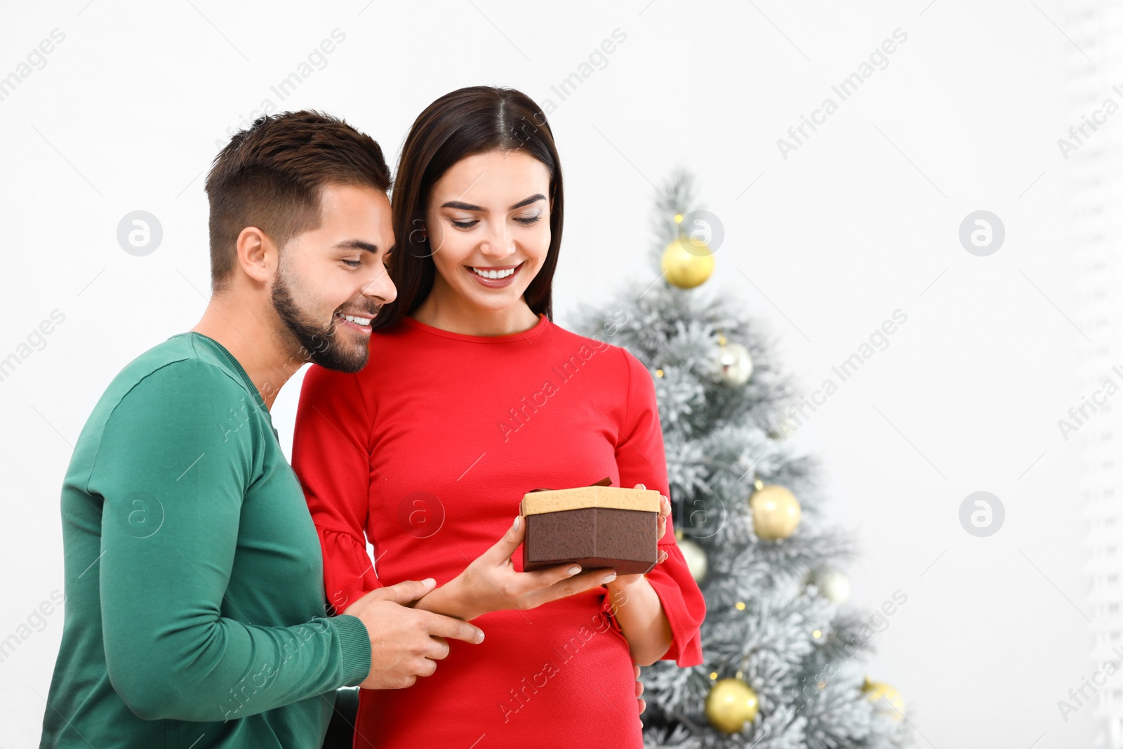 Photo of Happy young couple with Christmas gift at home