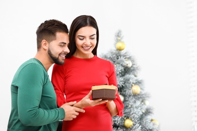 Happy young couple with Christmas gift at home