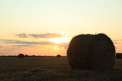Beautiful view of agricultural field with hay bale at sunset