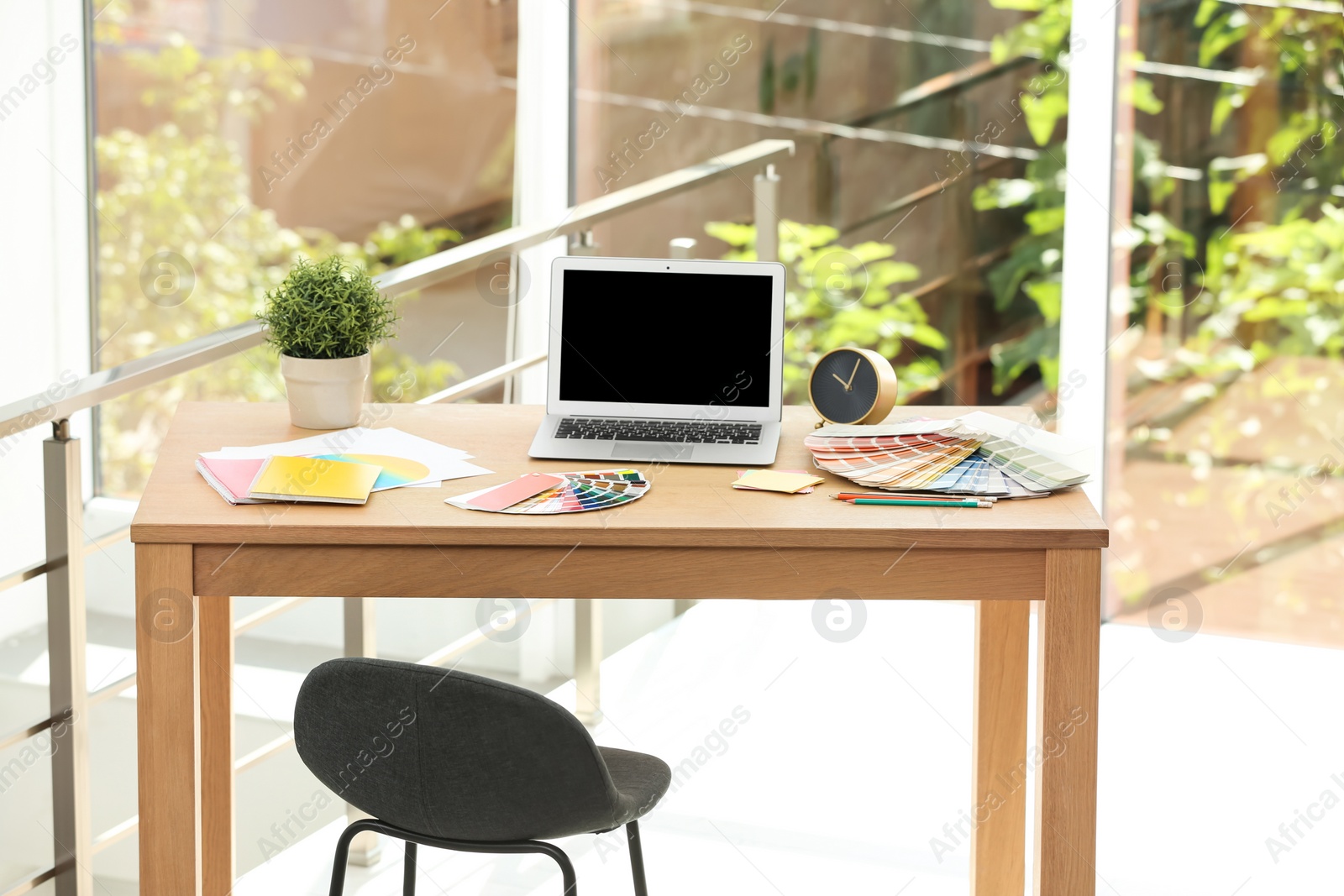 Photo of Designer's workplace with laptop and paint color palette samples on table