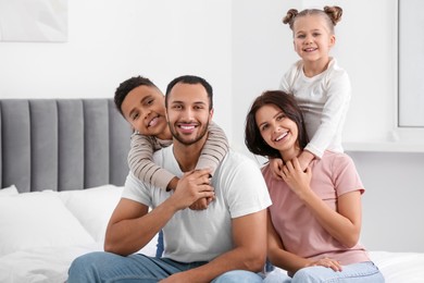 Photo of Happy international family spending time together on bed at home