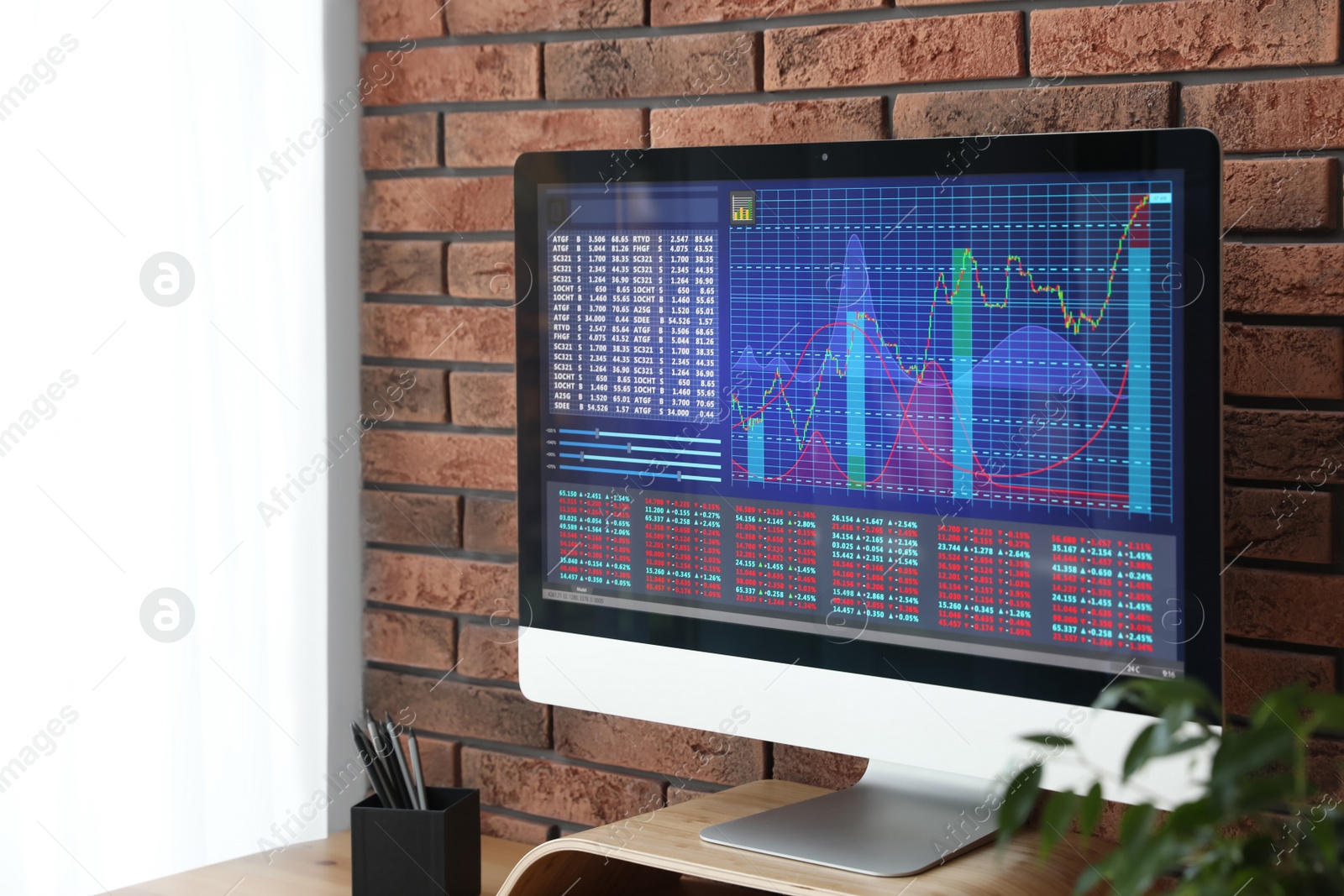 Photo of Modern computer with statistic information on wooden table near brick wall