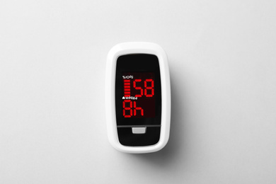 Modern fingertip pulse oximeter on white background, top view