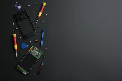 Photo of Disassembled mobile phone and repair tools on black background, flat lay. Space for text