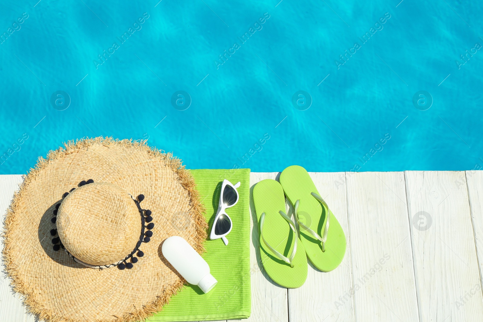 Photo of Flat lay composition with beach accessories on wooden deck near swimming pool. Space for text