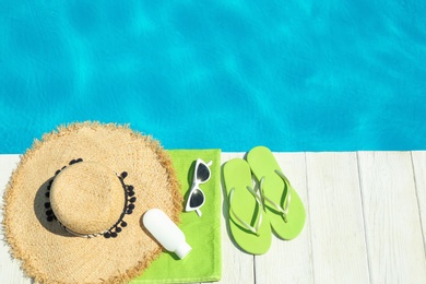 Photo of Flat lay composition with beach accessories on wooden deck near swimming pool. Space for text