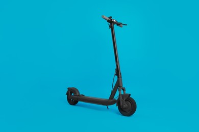 Photo of Modern electric kick scooter on light blue background