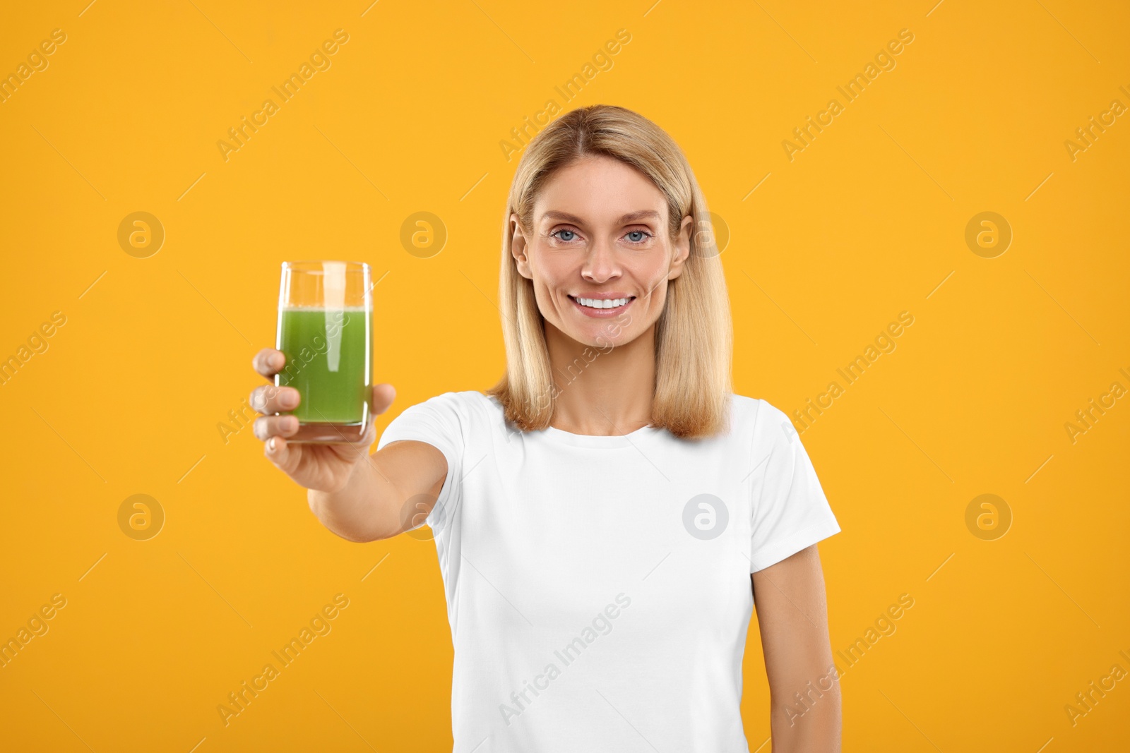 Photo of Happy woman with glass of fresh celery juice on orange background