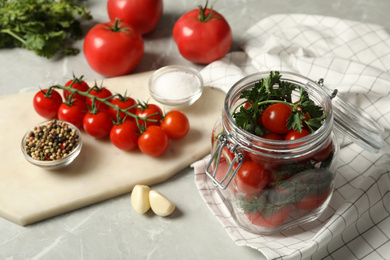 Photo of Pickling jar with fresh ripe cherry tomatoes and spices on grey table