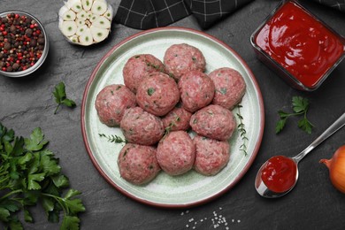 Many fresh raw meatballs and ingredients on black table, flat lay