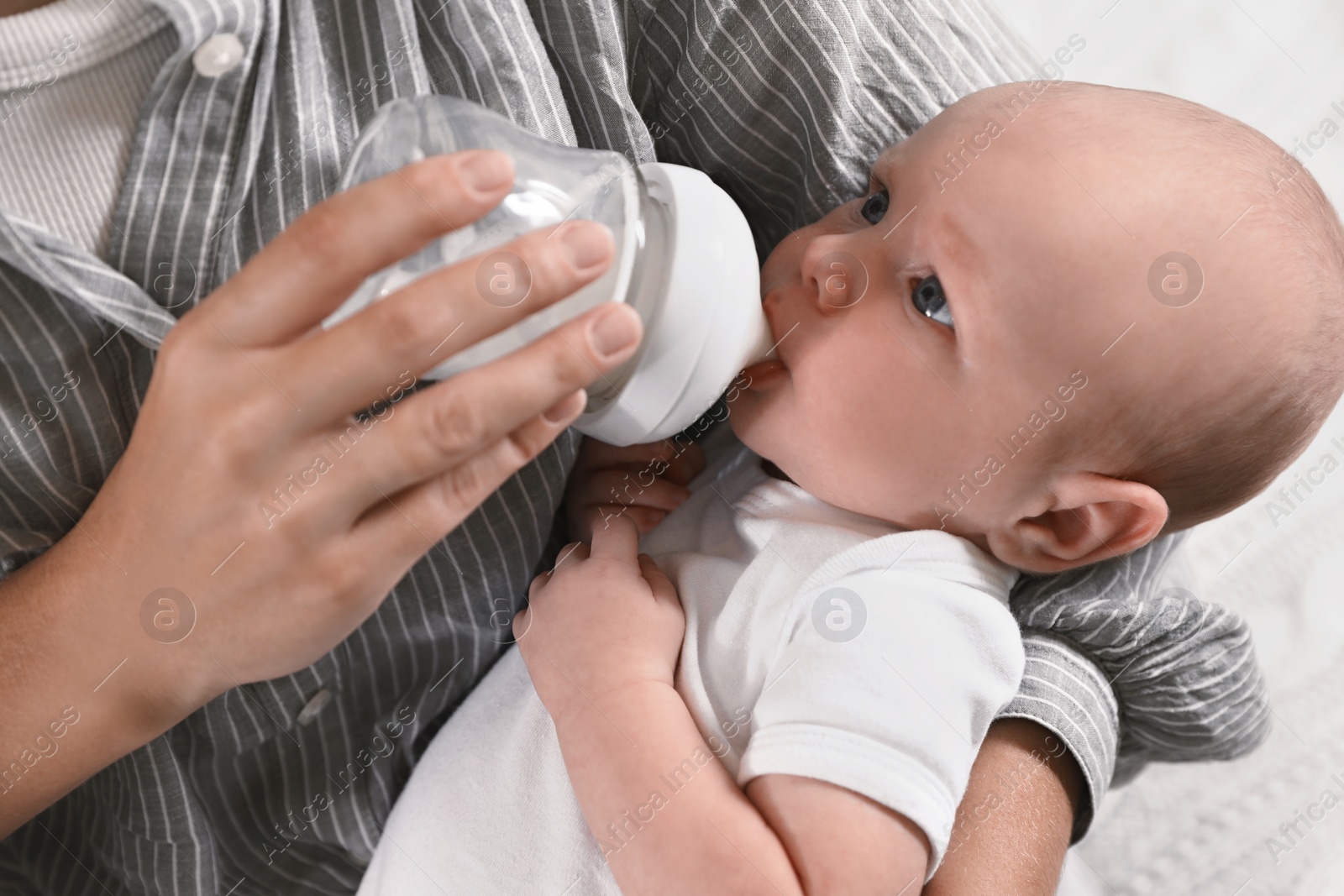 Photo of Mother feeding her little baby from bottle, closeup