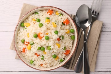 Photo of Bowl of delicious rice with vegetables served on white wooden table, flat lay