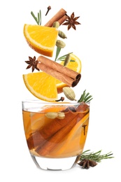 Cut orange and different spices falling into glass of mulled wine on white background 