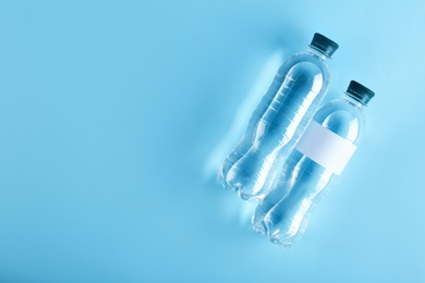 Photo of Bottles of water on color background, top view. Space for text