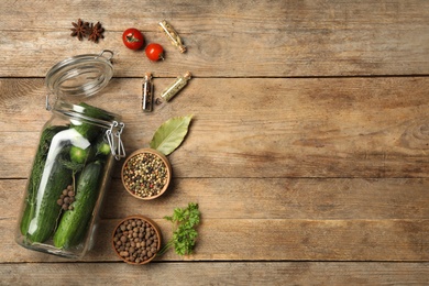 Photo of Pickling jar with fresh ripe cucumbers and spices on wooden table, flat lay. Space for text