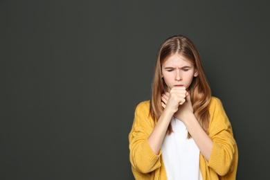 Photo of Teenage girl suffering from cough on dark background. Space for text