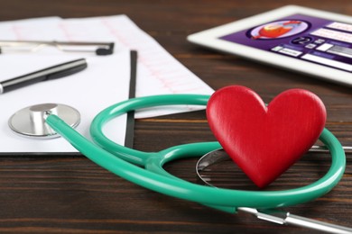 Photo of Stethoscope and red heart on wooden table, closeup. Cardiology concept