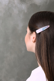 Photo of Young woman with beautiful hair clip on grey background