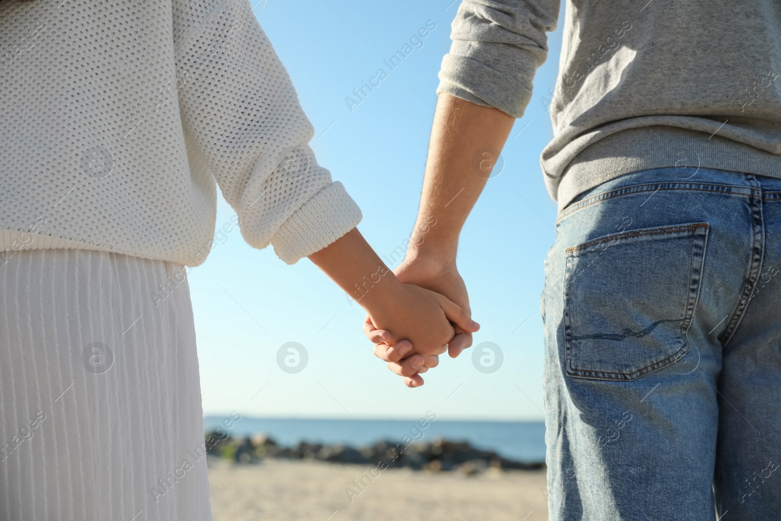 Photo of Young couple holding hands on beach, closeup. Honeymoon trip