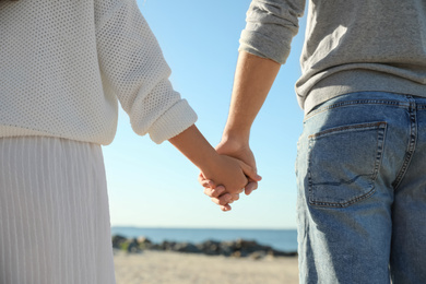 Young couple holding hands on beach, closeup. Honeymoon trip