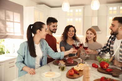 Happy people drinking wine while cooking food in kitchen