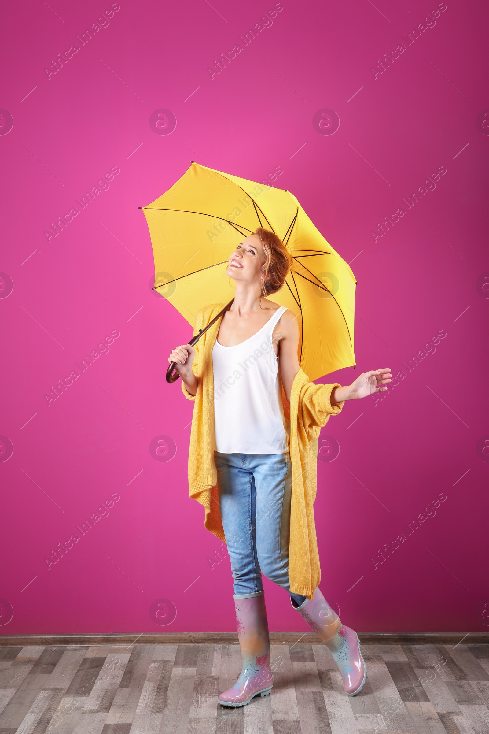 Photo of Woman with yellow umbrella near color wall