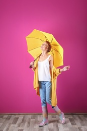 Photo of Woman with yellow umbrella near color wall